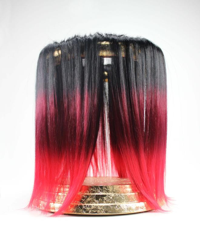 gold leaf circular stand with black and red hair draping over.